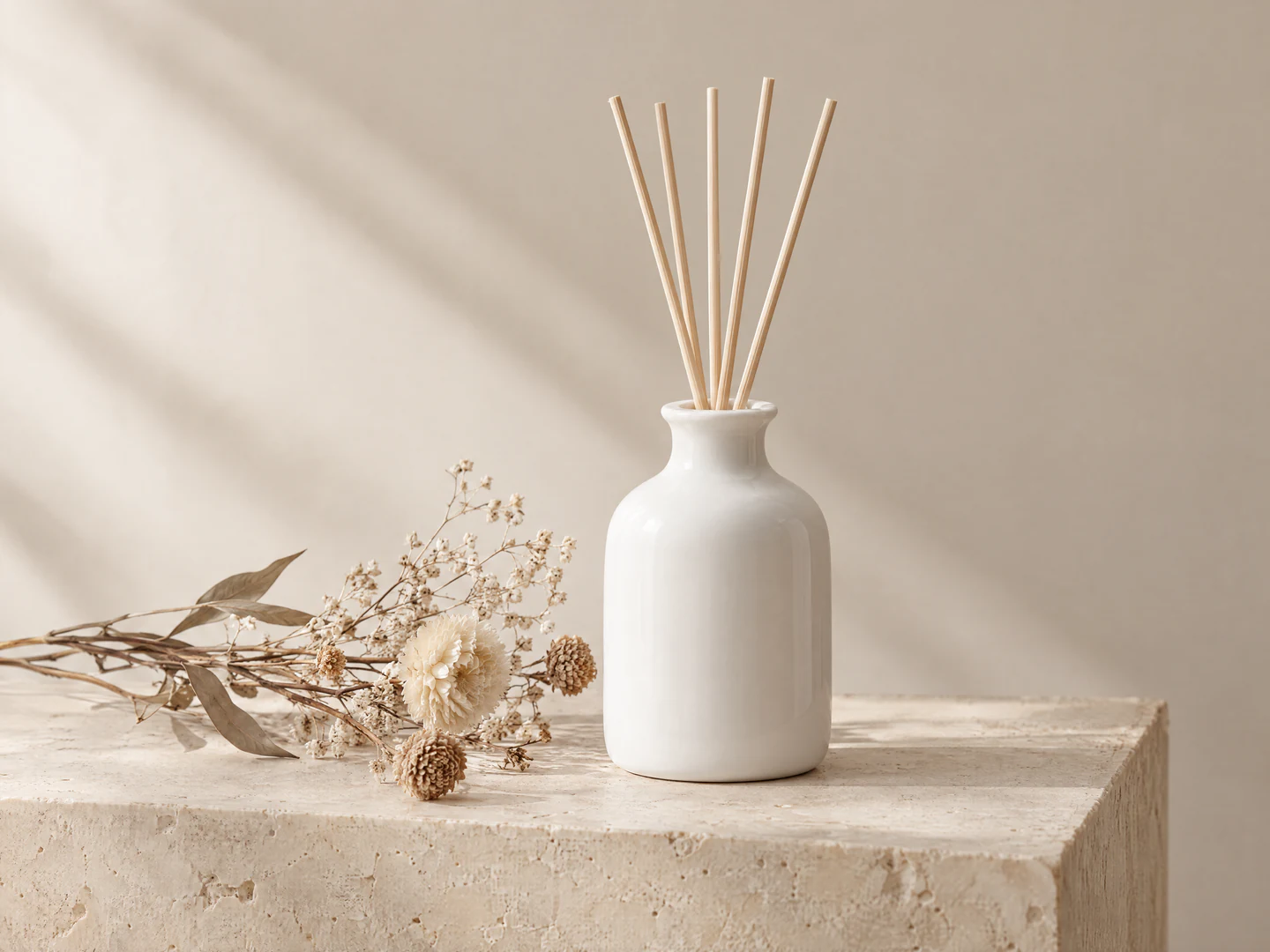 AI-generated product shot of a white ceramic reed diffuser and dried flowers on a beige stone block, with soft side light casting shadows on the wall